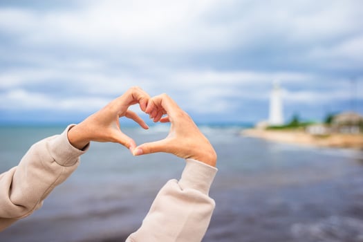 Female hands in the form of heart against the lighthouse photo