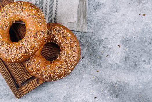 Healthy organic whole grain bagel on wooden board on concrete background table. Breakfast bread. Copy space, top view photo
