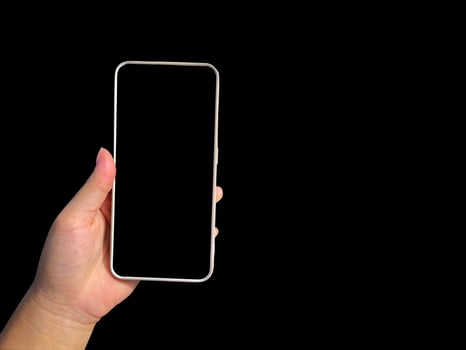 Hand holding a mobile phone at the screen, leaving a blank black space for text on a black background. soft and selective focus. photo