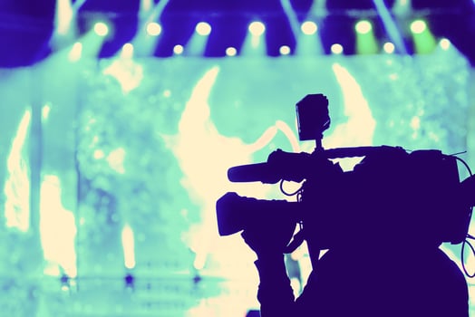 Professional Video camera operator working with his equipment, blue background photo
