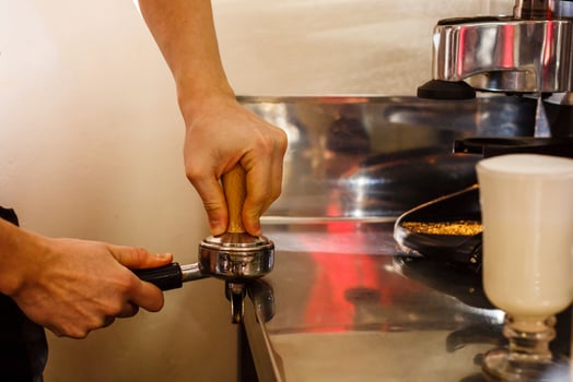 Closeup of male barista hand holding ground coffee for preparing espresso, service and preparation concept. photo