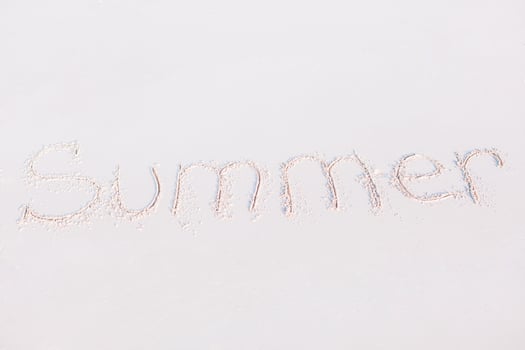 Word Summer handwritten on sandy beach with soft ocean wave on background photo