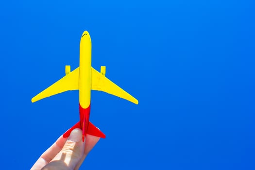 Small plane in female hand on background of blue sky photo