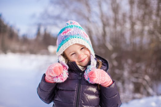 Portrait of little adorable girl in winter hat at snowy forest photo