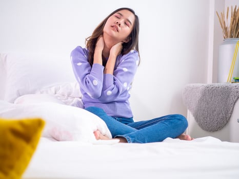 Asian woman feeling neck ache, suffering from painful feeling in neck in morning after sleeping on uncomfortable pillow at home or hotel room. photo