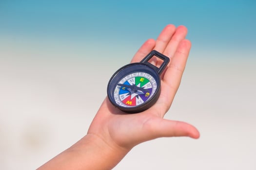 Little girl traveler with a compass in the hand on the beach photo
