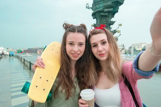 Two hipster urban girls with skateboard outdoors in sunset light. Closeup skatebords in female hands. Active sporty women having fun together in skate park. photo