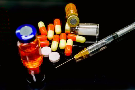 Vaccines in vial, capsules and white pill medicines with a plastic syringe on black background. photo
