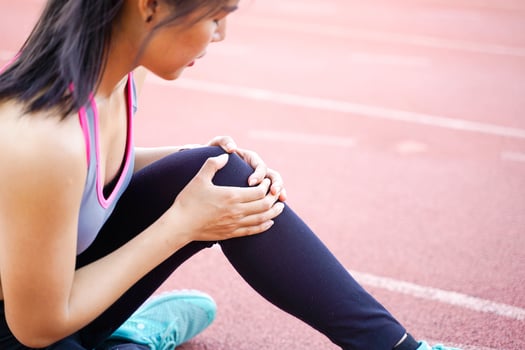 Closeup image of a young woman showing a knee injury after a workout. photo