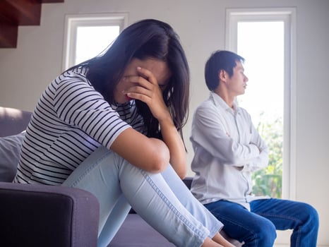 Asian couple have serious quarrel problems sitting on the sofa inside the house. the wife bowed sad. The husband turned his back after a conflict. photo