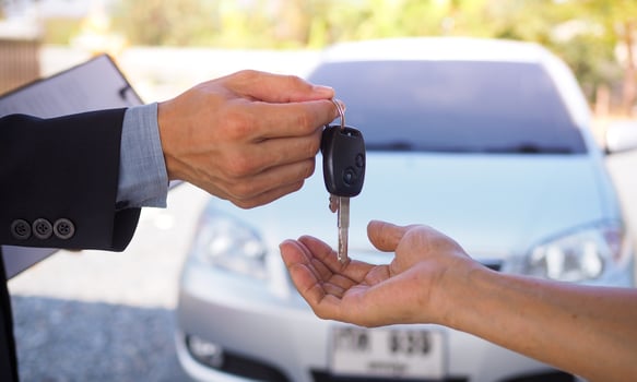 The salesman is handing over the keys to a new hire buyer. Auto business, car sale, deal, gesture and people concept - close up of dealer giving key. photo