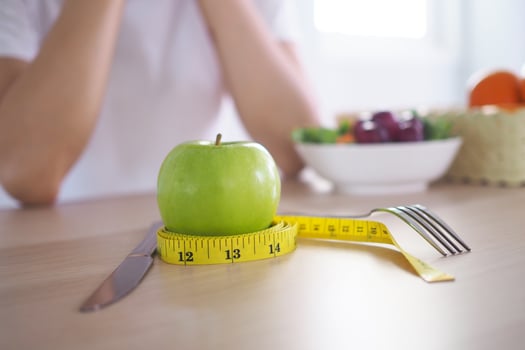 Tape measure around the green apple. Next there are milk and vegetable salad on the wooden table. Eating for good health and weight loss. Diet concept photo