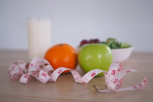 Focus at measuring tape - Healthy food with vegetable salad, orange, apple and milk. Concept Diet photo