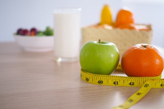 Tape measure around the green apple. Next there are milk and vegetable salad on the wooden table. Eating for good health and weight loss. Diet concept photo