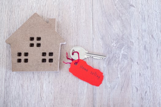 Key and red torn paper with house sales message on wooden background. Concept of selling home photo