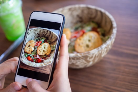 The girl's hand is taking pictures of the food on the table at home after ordering food online to eat at home. The concept of mobile phones to order food online photo
