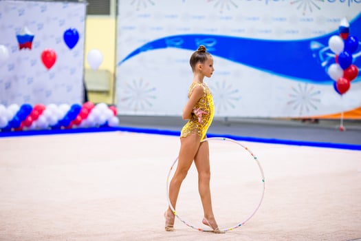 Beautiful little gymnast girl on the carpet on the competition photo
