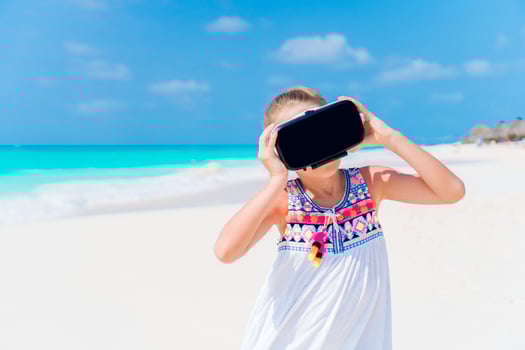 Little girl using VR virtual reality goggles. Adorable kid look into the virtual glasses on white beach photo