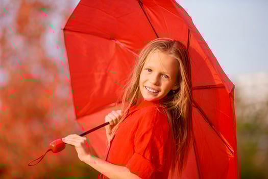 Happy child girl laughs under red umbrella photo