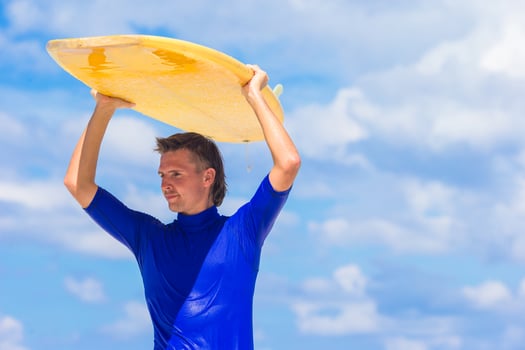 Happy young surf man at white beach with yellow surfboard photo