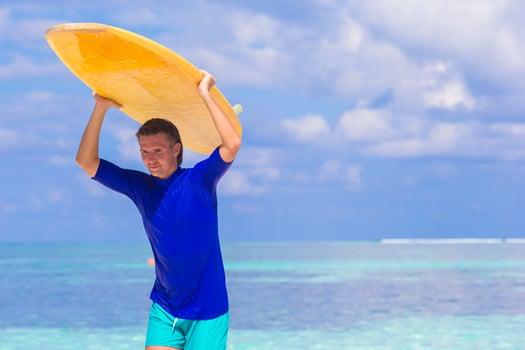 Happy young surf man at white beach with yellow surfboard photo