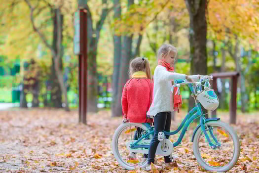 happy little girls riding a bike at beautiful autumn day outdoors photo