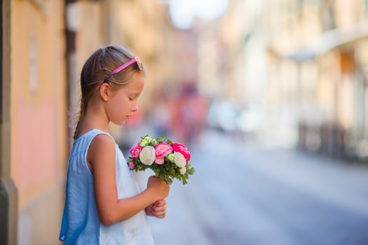 Adorable little girl with flowers bouquet walking in european city photo
