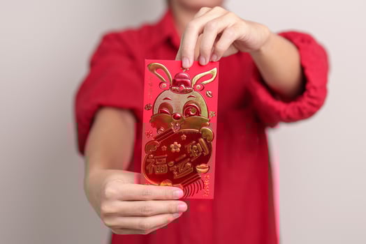 woman holding Chinese red envelope with golden rabbit and blessing word, money gift for happy Lunar New Year holiday. Chinese sentence means happiness, healthy, Lucky and Wealthy photo