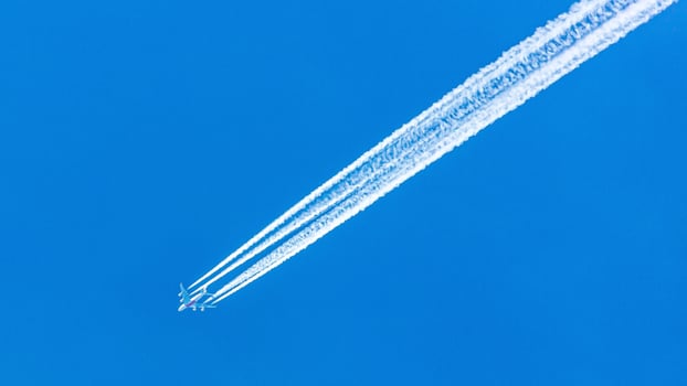 Four engined airplane during flight in high altitude with condensation trails photo