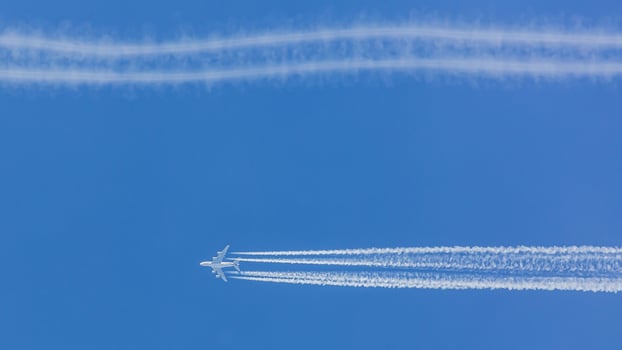 Four engined airplane during flight in high altitude with condensation trails photo