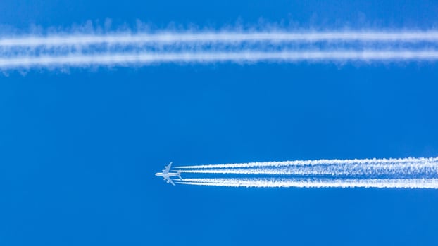 Four engined airplane during flight in high altitude with condensation trails photo