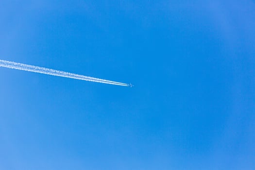 Two engined airplane during flight in high altitude with condensation trails photo