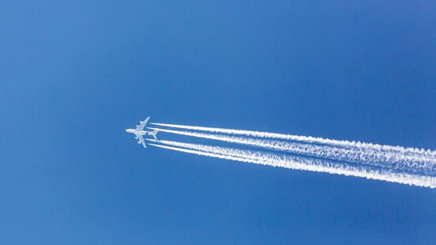 Four engined airplane during flight in high altitude with condensation trails photo