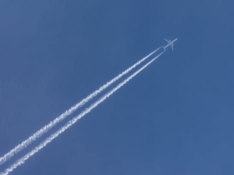 Airplane with condensation trail in blue sky photo