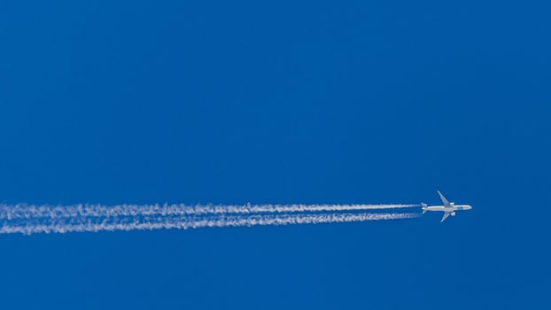Two engined airplane during flight in high altitude with condensation trails photo