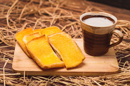 A cup of coffee and toast on a wooden board photo