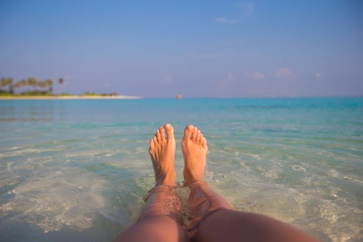 Female feet on white sandy beach and clear water photo