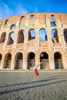 Adorable little active girl having fun in front of colosseum in Rome, Italy. Cute sporty kid making wheel background of famous attractive in Europe. photo