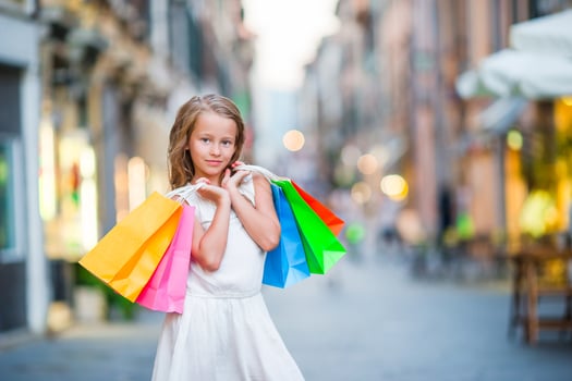 Portrait of adorable little girl walking with shopping bags outdoors in Rome. Fashion toddler kid in Italian city with her shopping photo