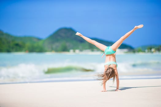 Beautiful little girl doing sporty exercises on the beach photo