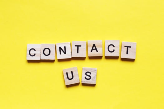 Word contact us made from wooden cubes on a yellow paper background. photo