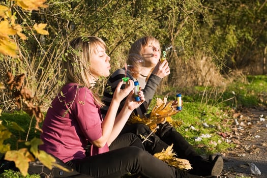 Two beauty young women starts up soap bubble in park photo