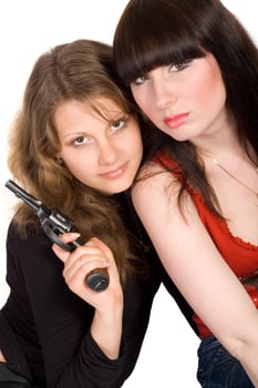 Two young women with a pistol. Isolated photo