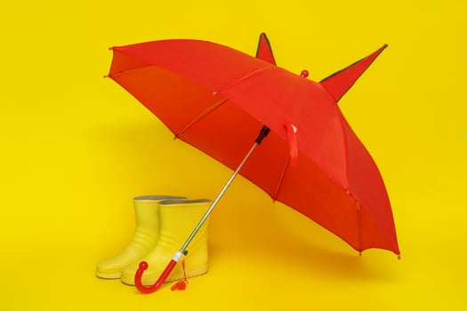 children's yellow rubber boots under a red children's umbrella on a yellow background photo