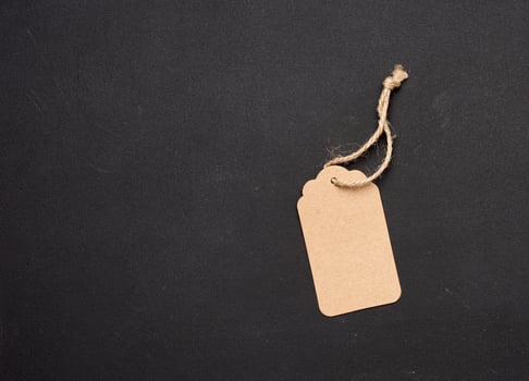 empty paper brown rectangular price tag on a rope on a black background photo