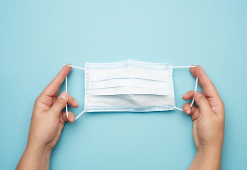 female hand holds a stack of disposable medical face masks against viral diseases photo