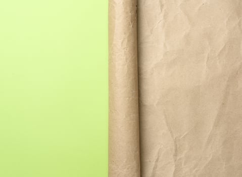 folded corner of a roll of brown paper on a green background photo
