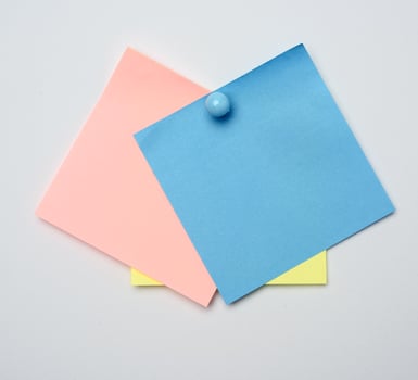 stack of colorful stickers pinned by blue button on white background photo