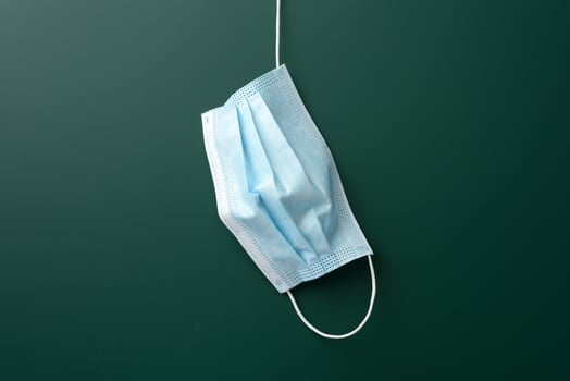 disposable medical mask hanging on blank green chalk board background photo