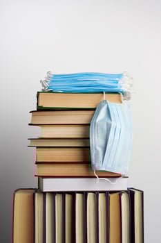 stack of various books and disposable medical masks on a white background, concept of visiting libraries photo